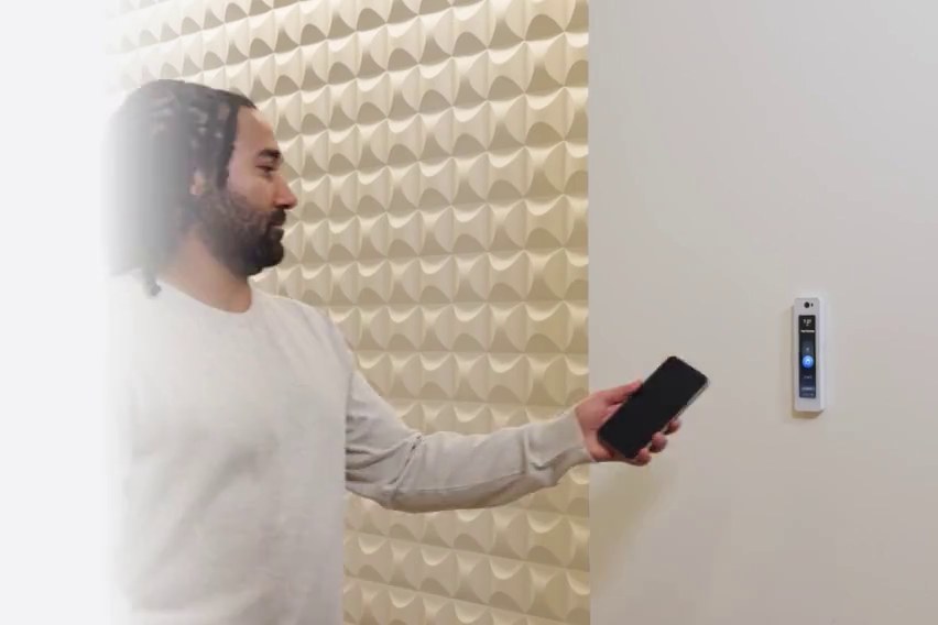 Resident opening a door with a phone at a wall-mounted access reader